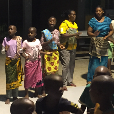 Moeders en kinderen zingen en dansen.